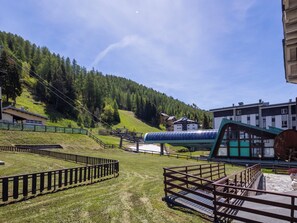 Una stazione sciistica con una seggiovia, edifici e un pendio boscoso.
