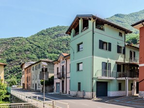 Ein mehrstöckiges Gebäude mit Balkonen, eine Straße davor und eine gebirgige Kulisse.