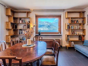 Un coin repas avec une table en bois, des chaises et des étagères remplies de livres.