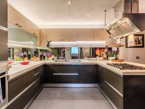 A modern kitchen with a central island, stainless steel appliances, and a large window providing natural light. - La Torre a Dorio by Interhome (Dorio)