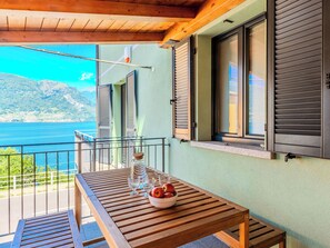 Ein Balkon mit Holztisch, Obstschale und einer Flasche.