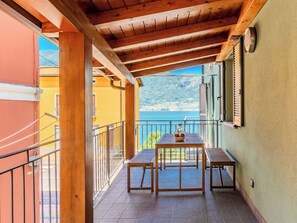A balcony with a wooden table and chairs, a view of the sea, and a mountain in the background. - La Torre a Dorio by Interhome (Dorio)