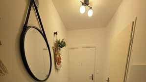 A hallway with a mirror, a ceiling fan, and a door. - Escale Zen & Loggia: 5 min from the train station (Direct Paris) + Parking (Évry-Courcouronnes)