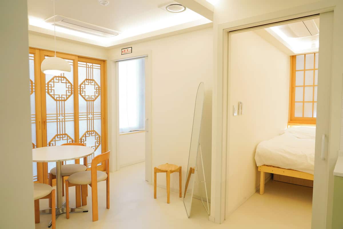Una habitación con cama, una mesa con sillas, un espejo y una puerta corredera.