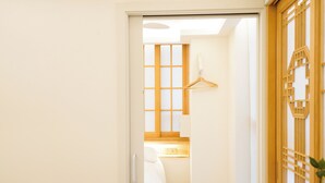 Hotellihuone, jossa on sänky, puinen vaatekaappi, riippuvalaisin ja ikkuna, josta on näkymä.