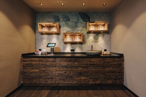 Un mostrador de recepción con armarios de madera, un lavabo de piedra y luminarias fijadas a la pared.