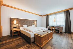 Una habitació d'hotel amb un llit gran, taules de nit, una panxa de fusta, un escriptori i una cadira.