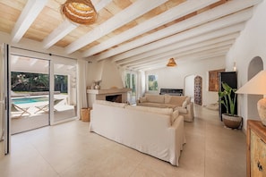 A spacious living area with a fireplace, a sofa, a television, and a view of the outdoors. - La Canova - Swimming Pool | Terrace | Mallorca (Mallorca)