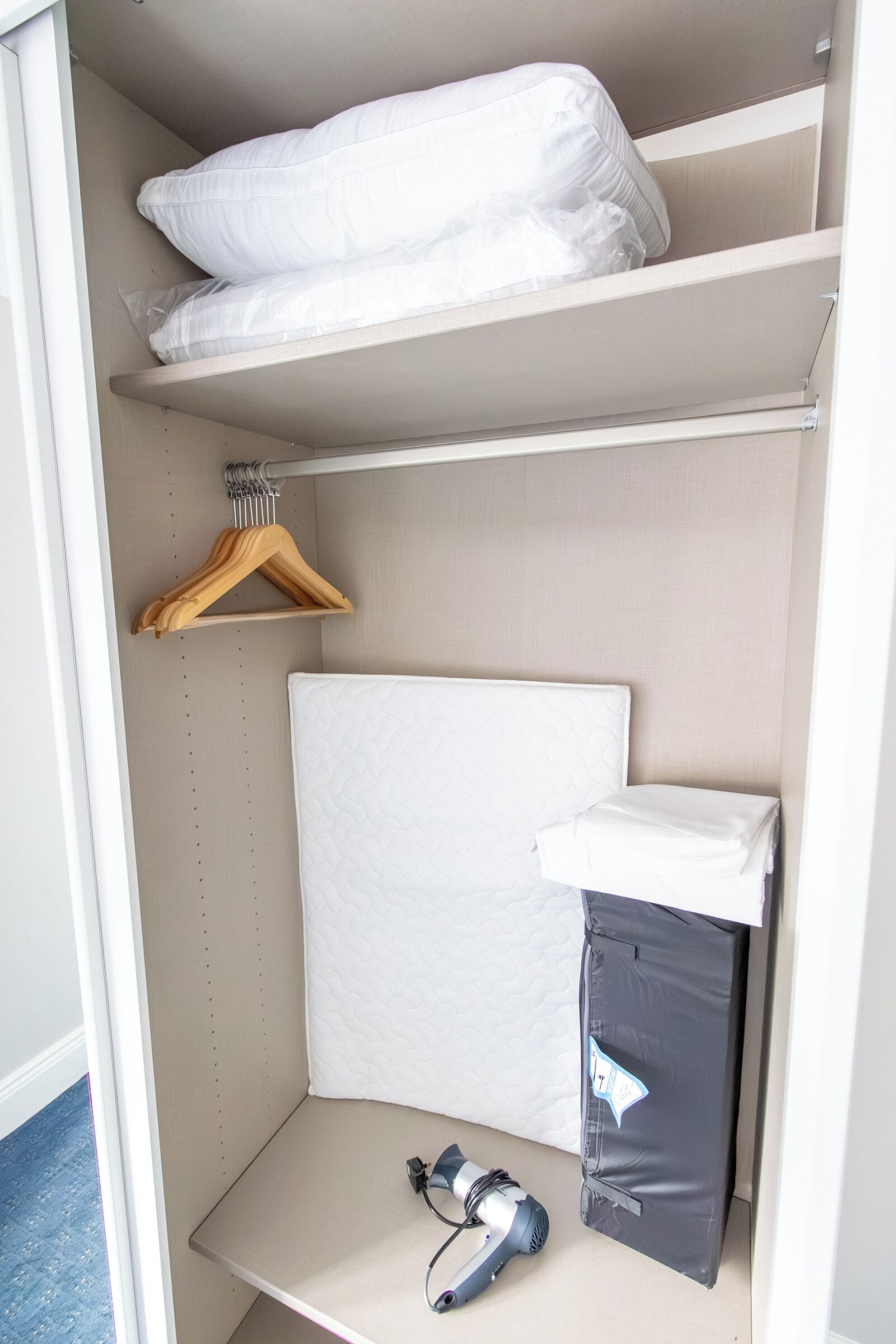 A closet with shelves, a hanging rack, and a mattress.