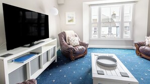 Una sala de estar con televisor de pantalla plana, sillón de cuero y una mesa de centro.