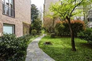 A stone pathway leading through a well-maintained garden with various shrubs and trees. - Visconti di Modrone, 18 - Small nest in central location (Milan)