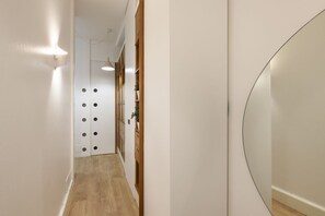 Ein Flur mit Holzakzenten, einer weißen Wand und einem runden Spiegel.