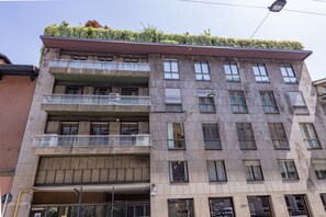 A multi-story building with balconies, a flat roof with greenery, and a visible ground floor entrance. - Visconti di Modrone, 18 - Small nest in central location (Milan)