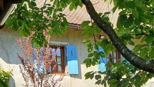 A courtyard with a table and chairs, a tree, and a building with blue shutters. - Ferme Berger-By, a family home in the heart of the 2 lakes region (Pressins)