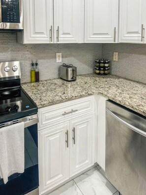 A kitchen with white cabinets, a stainless steel range, a toaster, and a spice rack. - Penny Cove - Stone Mountain (Stone Mountain)
