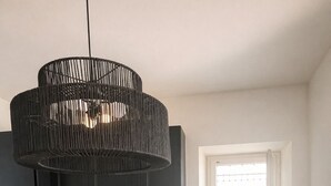 A modern kitchen with dark cabinets, a marble backsplash, a wooden dining table with a fruit bowl, and a black pendant light. - House Awaya Taormina Cathedral - Villa (Taormina)
