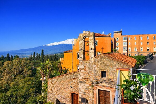 A stone building with a bell tower, a red-roofed building, and a mountain in the background. - House Awaya Taormina Cathedral - Villa (Taormina)