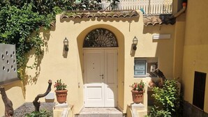 A set of stone steps leading to a white door, flanked by potted plants and a tiled floor. - House Awaya Taormina Cathedral - Villa (Taormina)