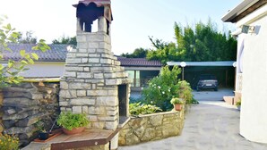A stone fireplace, potted plants, a garage, and a covered carport. - Charming Apartment in Zambratija With sea View (Umag)