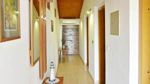 A hallway with wooden steps, a stone wall, and doors leading to rooms. - Charming Apartment in Zambratija With sea View (Umag)
