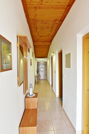 Ein Flur mit Holzstufen, einer Steinwand und Türen zu Zimmern.