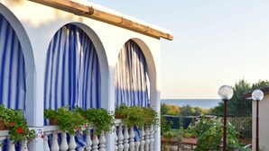 A building with three arched windows, a balcony with white balustrades, and a view of the sea. - Charming Apartment in Zambratija With sea View (Umag)