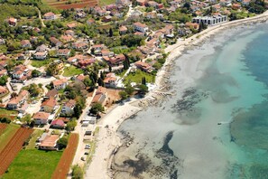 Vista aèria d'una zona residencial a la costa, amb cases, una platja i aigües blaves cristal·lines.