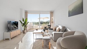 En moderne stue med et fladskærms-tv, en sofa, et sofabord og et spiseområde med stole og et bord.
