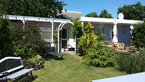 A house with a covered patio, a lawn, and a garden with various plants. - Holiday Home in Dranske (Dranske)