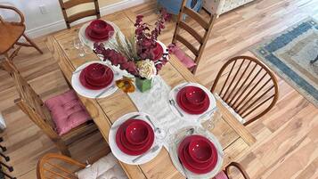 A dining table set with red plates, white napkins, and a vase with flowers.
