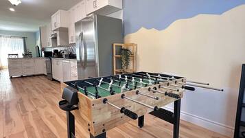 A modern kitchen with a foosball table, stainless steel appliances, and a view of the outdoors.
