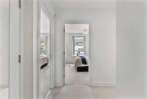 A hallway leading to a bedroom with a bed, a window, and a hanging light fixture. - Nordic Abode in Central Reading - Balcony (Reading)