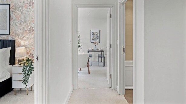 A hallway leading to a dining area with a table and chairs, a framed picture on the wall, and a plant on a side table. - Nordic Abode in Central Reading - Balcony (Reading)