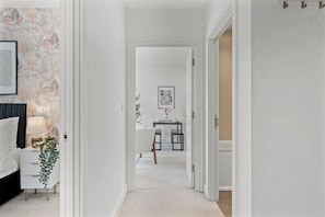 A hallway leading to a dining area with a table and chairs, a framed picture on the wall, and a plant on a side table. - Nordic Abode in Central Reading - Balcony (Reading)