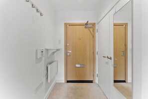 A hallway with a wooden door, a mirror, a light switch, and a thermostat. - Nordic Abode in Central Reading - Balcony (Reading)