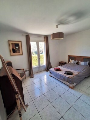 A bedroom with a bed, a desk, a chair, a picture frame, and a window with curtains. - Villa des Dentelles in Vacqueyras (Vacqueyras)