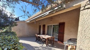 Un patio con mesa y sillas, una puerta corrediza de vidrio y una estufa a gas.