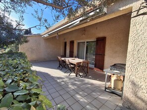 A patio with a table and chairs, a sliding glass door, and a gas stove. - Villa des Dentelles in Vacqueyras (Vacqueyras)