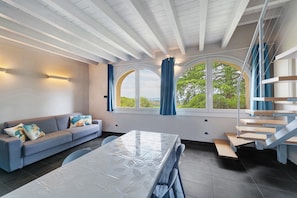 Un intérieur moderne avec un canapé, une table, un escalier et de grandes fenêtres.