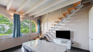 A modern room with a dining table, a TV, and a staircase.