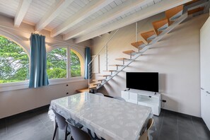 Ein modernes Zimmer mit Esstisch, Fernseher und einer Treppe.