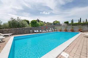 Ein rechteckiger Swimmingpool mit klarem, blauem Wasser, umgeben von einer Steinmauer, und ausgestattet mit zwei Rettungsringen.