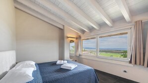 A bedroom with a bed, a window with curtains, and a view of the landscape.
