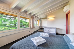 Ein Schlafzimmer mit einem großen Bett, einem Fenster mit Vorhängen, einem Heizkörper und einer Wand-Klimaanlage.
