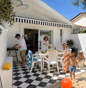A patio area with a checkered floor, outdoor seating, and a grill.