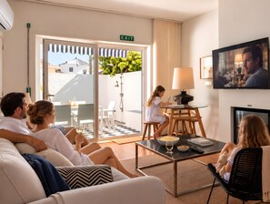 Une chambre d’hôtel avec un balcon, une télévision et un coin repas comprenant des chaises et une table.
