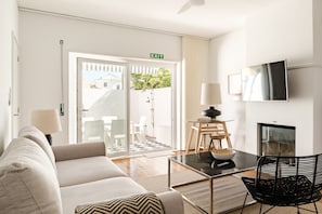 Une chambre d’hôtel moderne équipée d’un canapé, d’une table à manger avec des chaises, d’un téléviseur fixé au mur et d’un panneau de signalisation indiquant la sortie.
