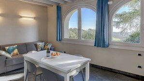 Ein modernes Wohnzimmer mit einem weißen Tisch, einem grauen Sofa und Blick durch große Bogenfenster.