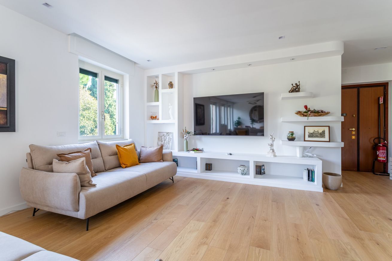 A modern living room with a sofa, TV, and white shelving unit.