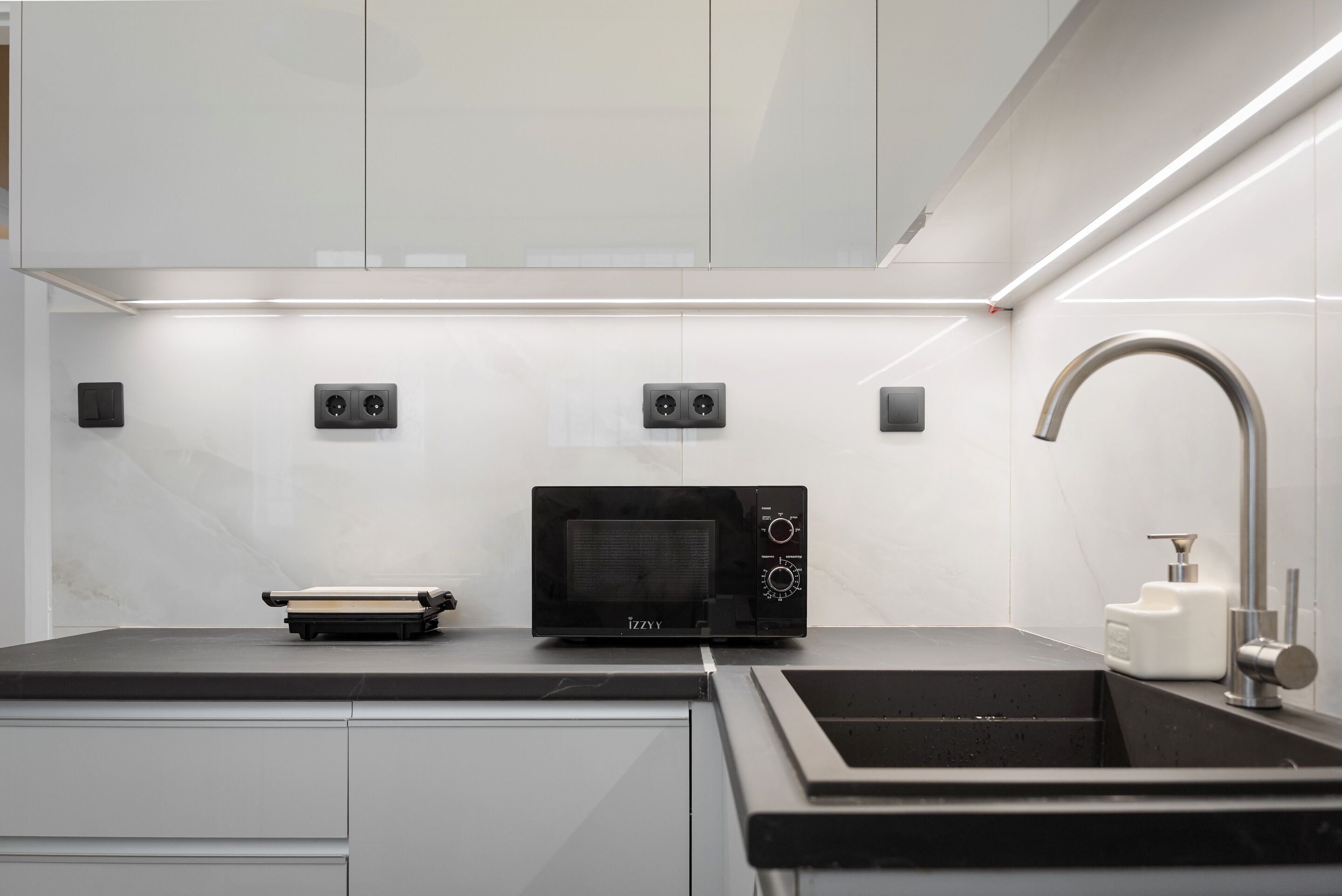 A modern kitchen with a built-in microwave, a sink, and a faucet.
